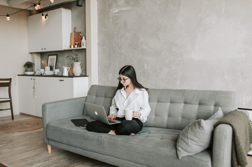 Woman sitting on couch with laptop and coffee mug