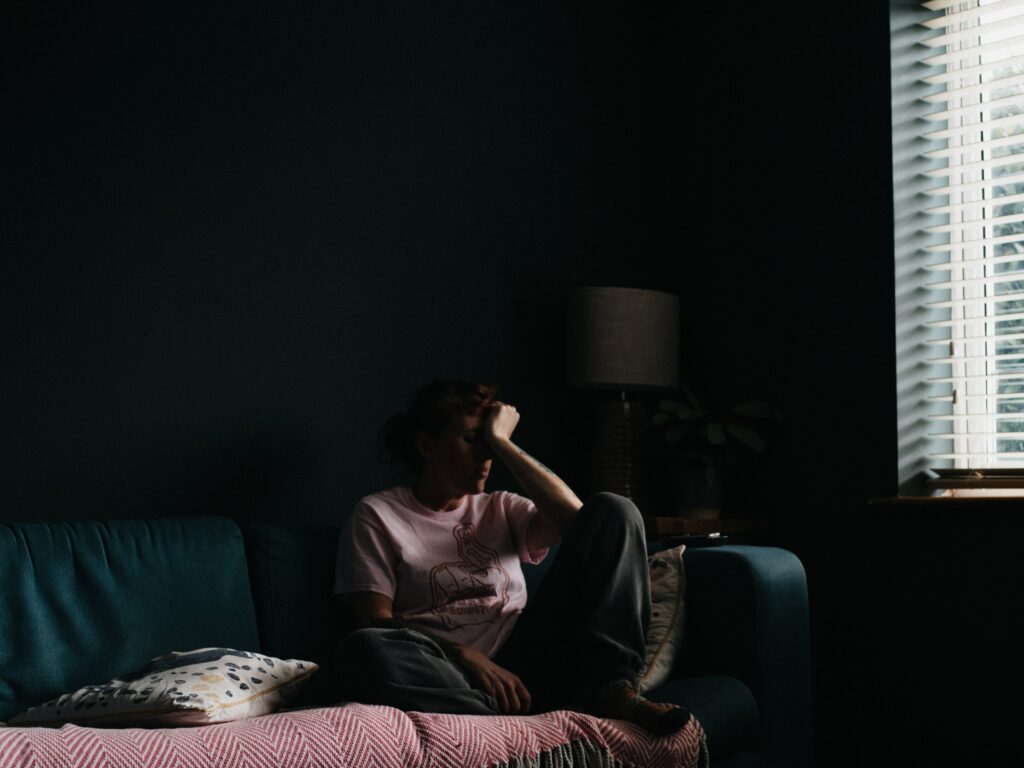 Woman depressed sitting on couch in the dark 