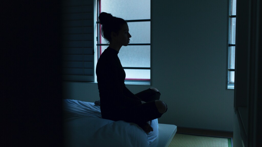 Young woman sitting on edge of bed