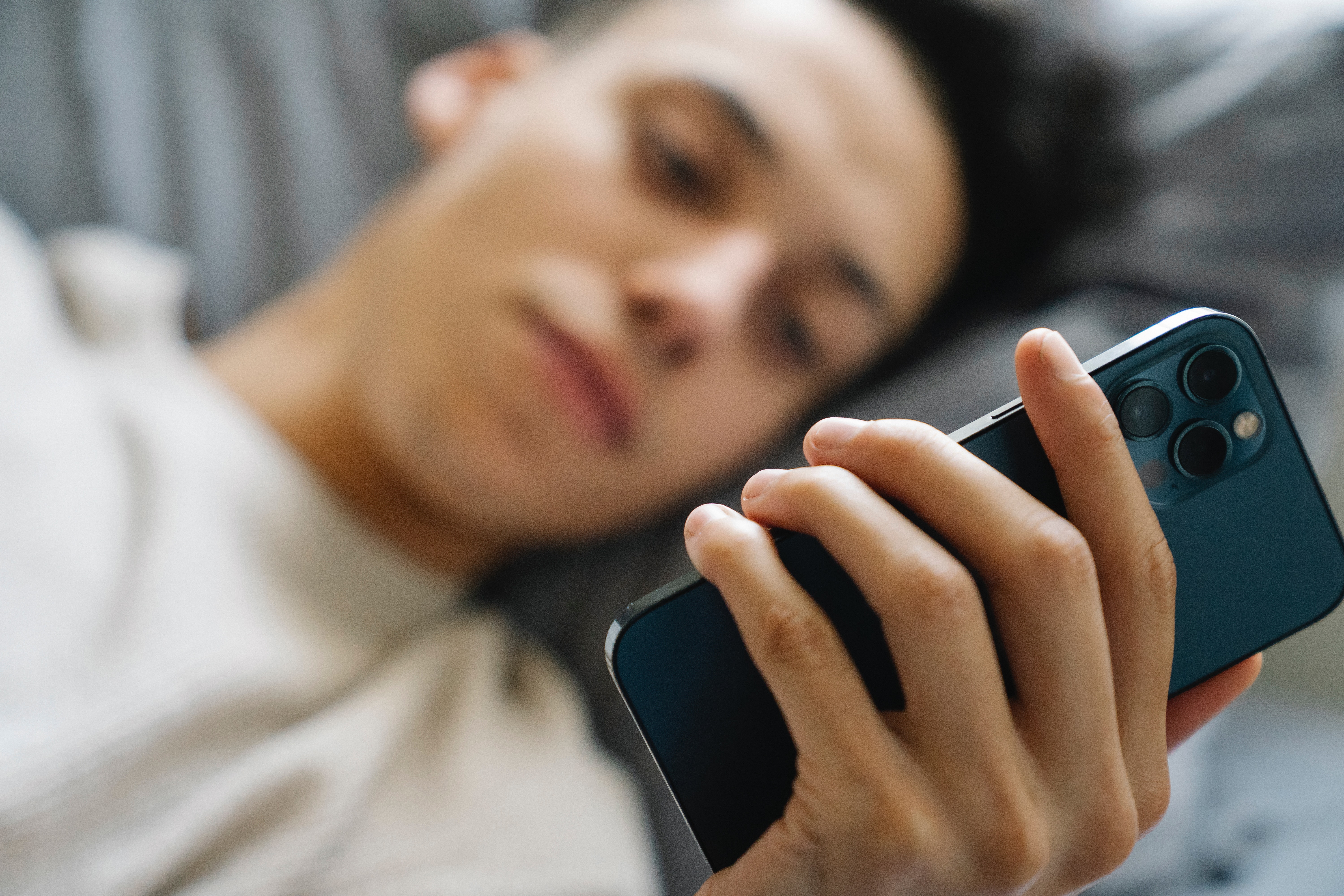 Man laying in bed scrolling on mobile device 