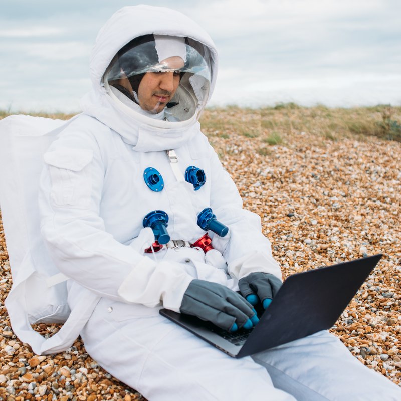 Man in astronaut suit typing on computer