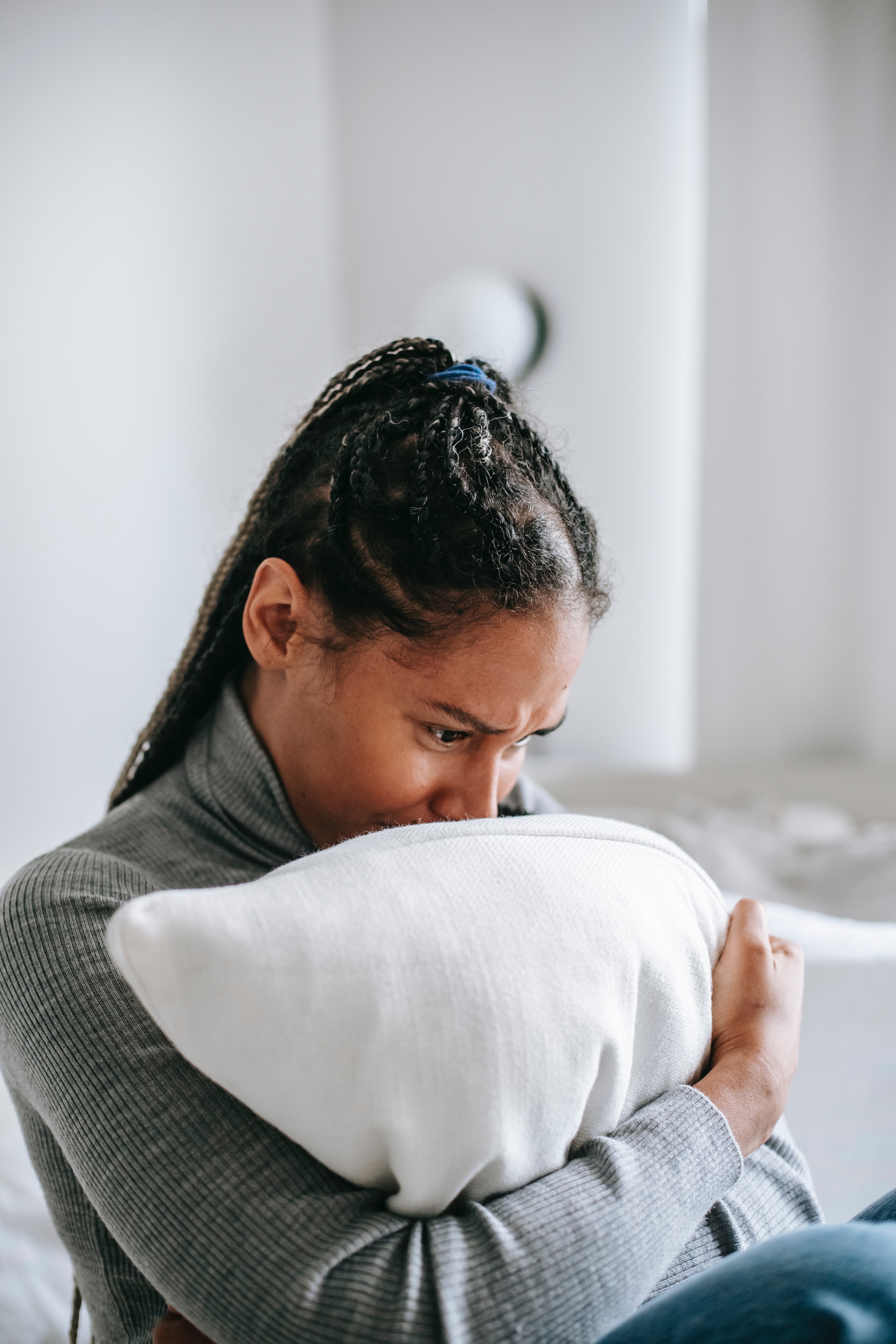 Grieving woman sitting on the bed holding a pillow