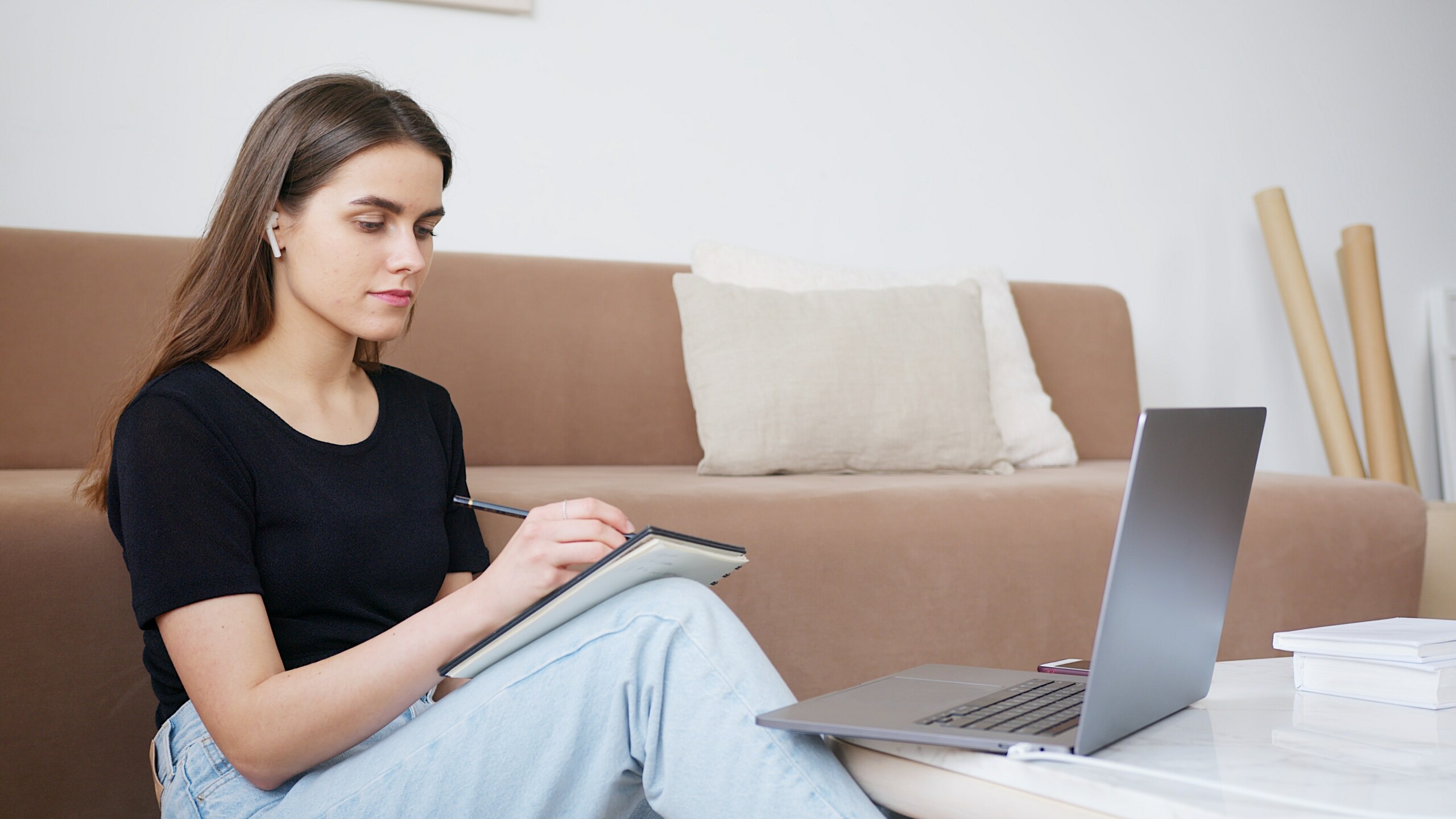 Woman in front of computer with notebook and pen